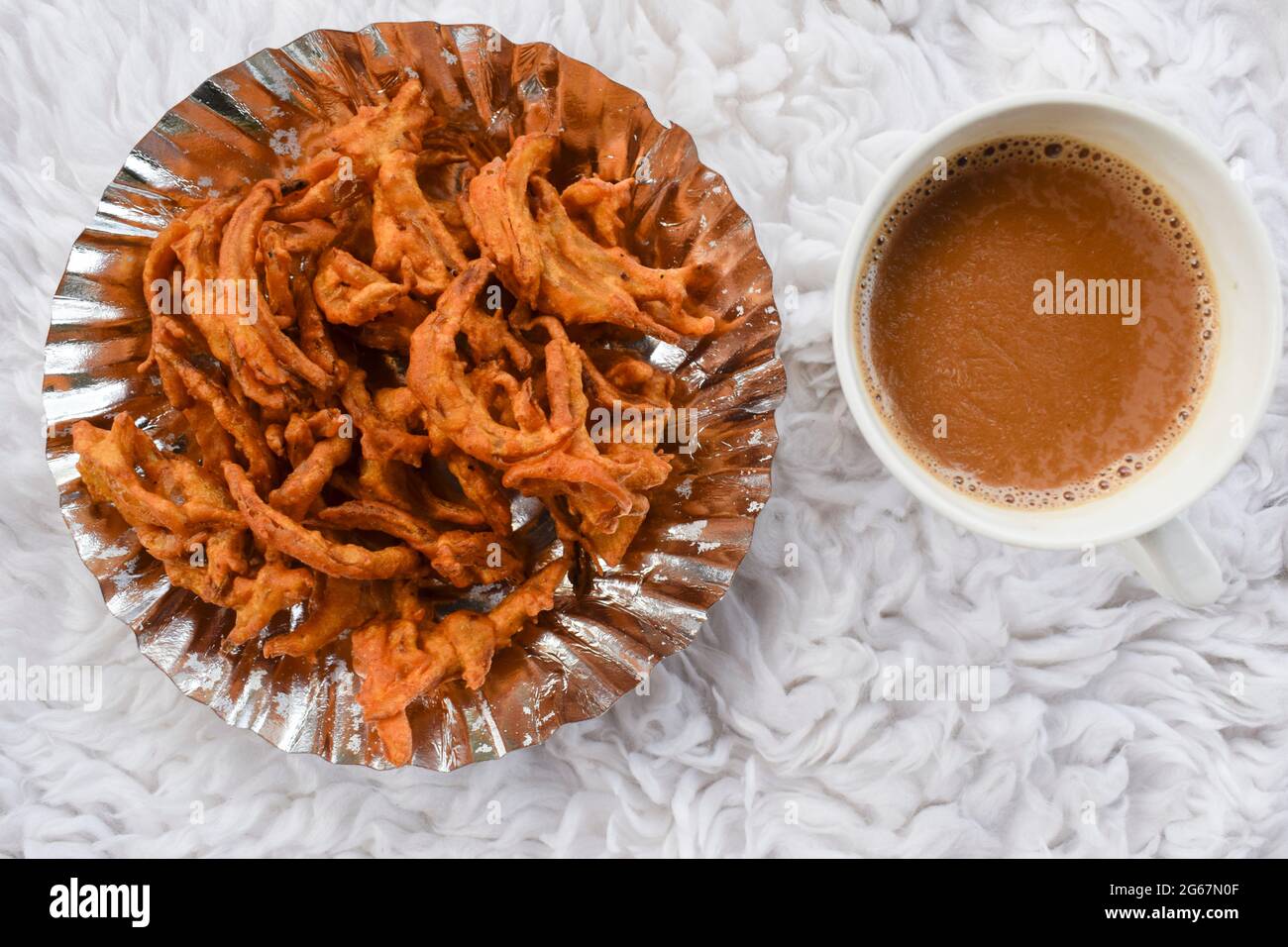 Délicieux en-cas indiens Pakoda d'oignon à base de farine de graminée et frite. Tea Time, des collations populaires faites maison en inde. Servi dans une assiette en papier et du thé masala Banque D'Images