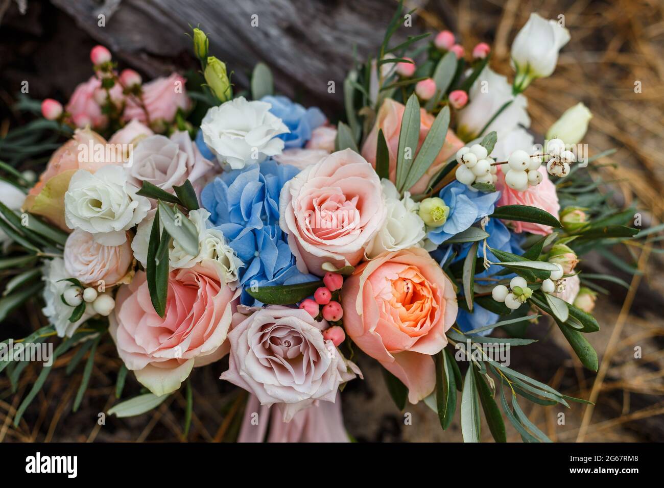 Un délicat et très beau bouquet de mariage de roses, de verdure, d'eustoma et d'hortensia sur un fond de souche sèche. Fleuristes de la mariée dans les tons pastel Banque D'Images