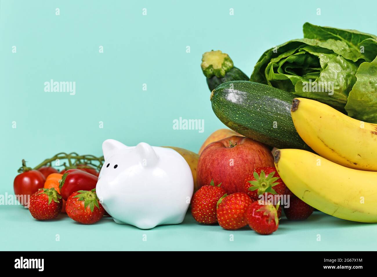 Concept pour les coûts d'une saine alimentation ou d'économie d'argent lors de l'achat de nourriture. Légumes et fruits à côté de la berge sur fond bleu avec espace de copie Banque D'Images
