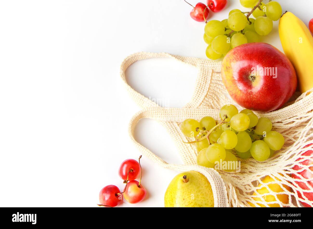 Fruits mûrs bio dans un sac en mesh écologique sur fond blanc. Sac à cordes tendance pour faire du shopping. Concept de saine alimentation et de mode de vie durable. Banque D'Images