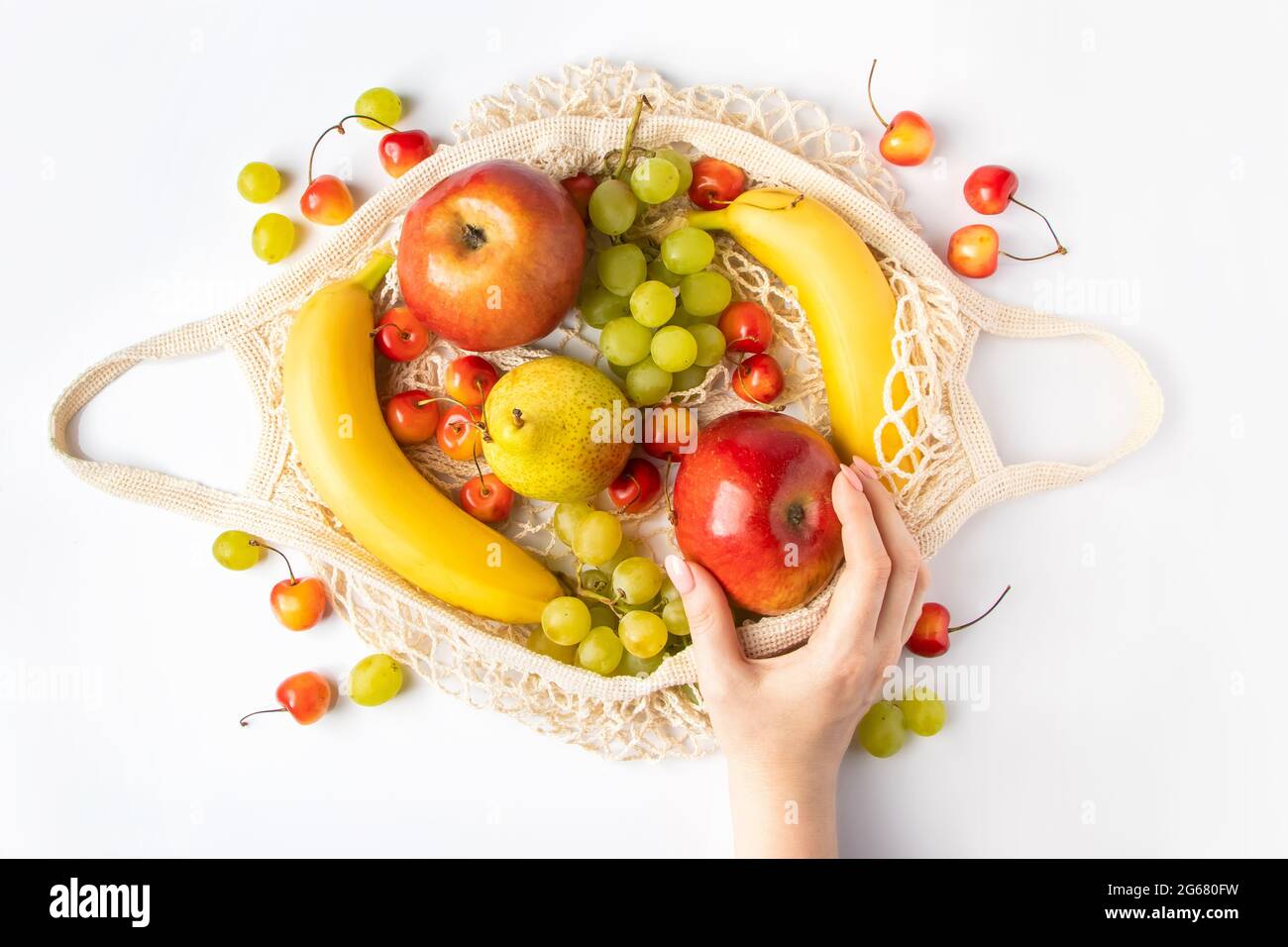 Une femme met des fruits mûrs dans un sac en filet écologique pour faire du shopping. Les mains des femmes tiennent un sac à ficelle de coton avec des produits agricoles biologiques. Vie durable Banque D'Images