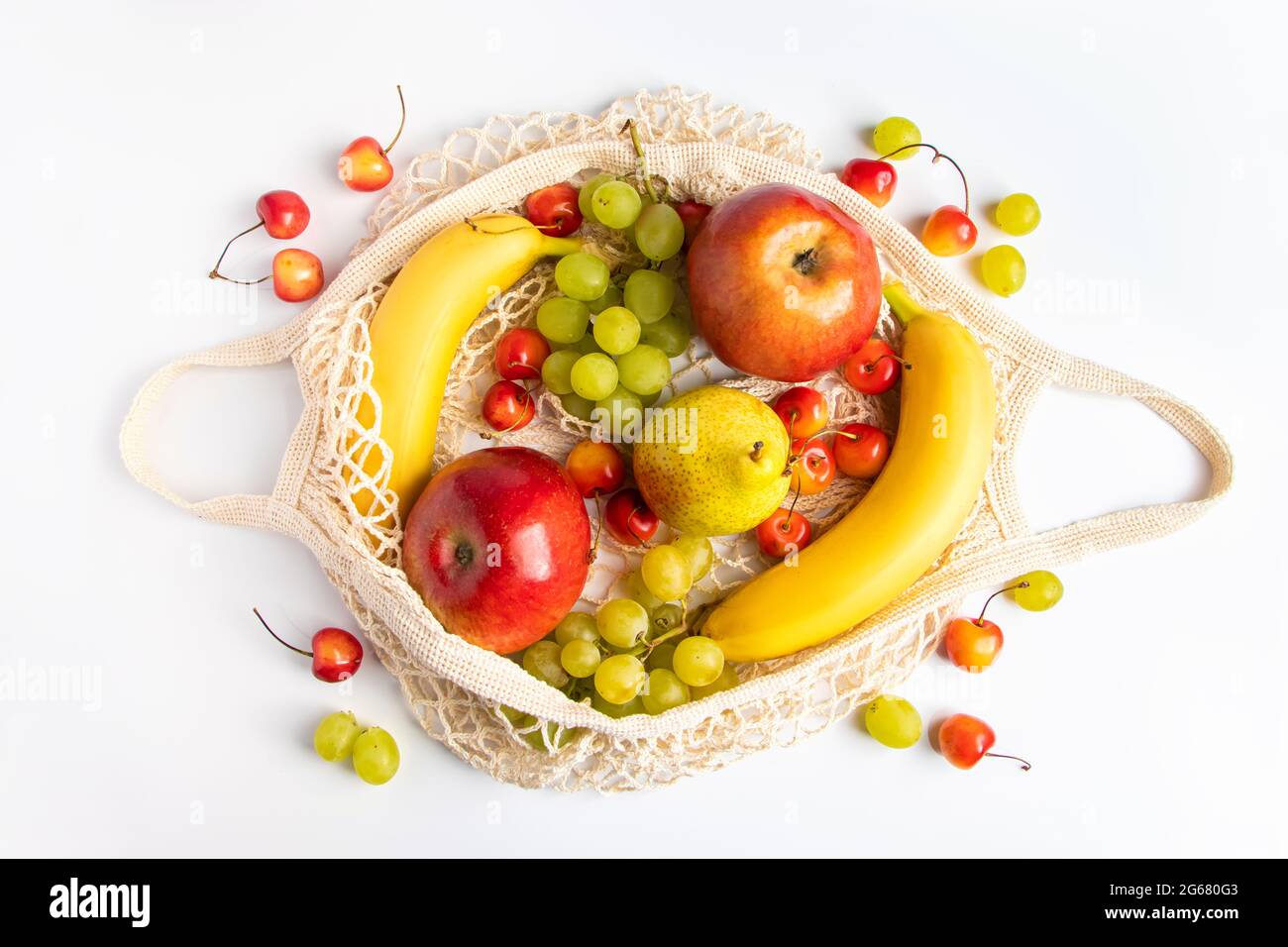 Fruits mûrs bio dans un sac en mesh écologique sur fond blanc. Sac à cordes tendance pour faire du shopping. Concept de saine alimentation et de mode de vie durable. Banque D'Images