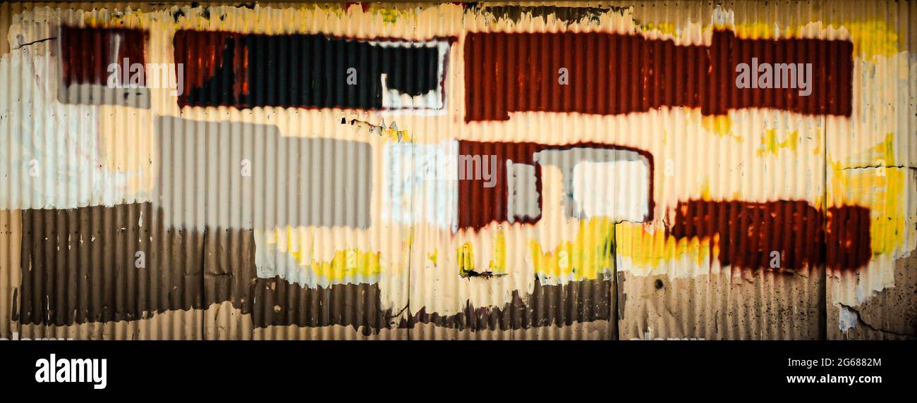 Un vieux bâtiment industriel avec une porte de garage en métal ondulé grasseuse peinte avec des blocs multicolores de peinture de recouvrement de graffiti, comme Rothko Banque D'Images