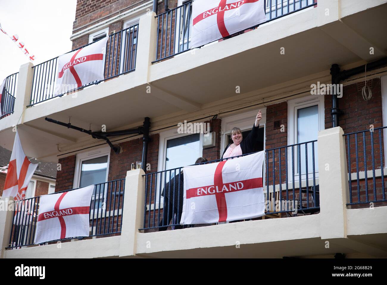 Autre résident vu sur le balcon et prêt à se joindre à regarder le match.UN fan de football, Chris Ralph Dewes, Organisé la décoration de plus de 400 drapeaux St George exposés dans le domaine Kirby dans le sud-est de Londres avec d'autres résidents avant le début du tournoi de l'UEFA Euro 2020. La tradition de la propriété de mettre des centaines de drapeaux de St George a été depuis l'Euro 2012 et chaque fois les résidents ont réussi à placer plus de drapeaux dans la propriété. Au cours de chaque match de l'équipe d'Angleterre, Chris sera l'hôte et invitera d'autres résidents à se joindre à l'observation. Il a dit que tous les drapeaux resteraient Banque D'Images