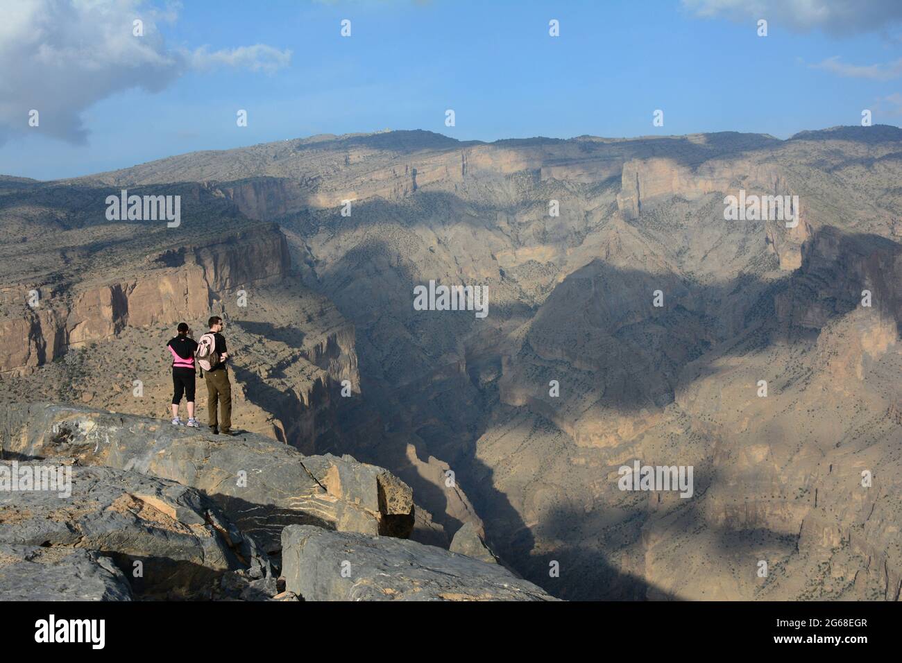 OMAN. LES MONTAGNES DE HAJAR. COUPLE DE RANDONNEURS REGARDANT LES JABAL SHAMS ET SON CANYON DE 1 500M DE PROFONDEUR. UN SENTIER DE RANDONNÉE SE TROUVE À L'INTÉRIEUR. Banque D'Images