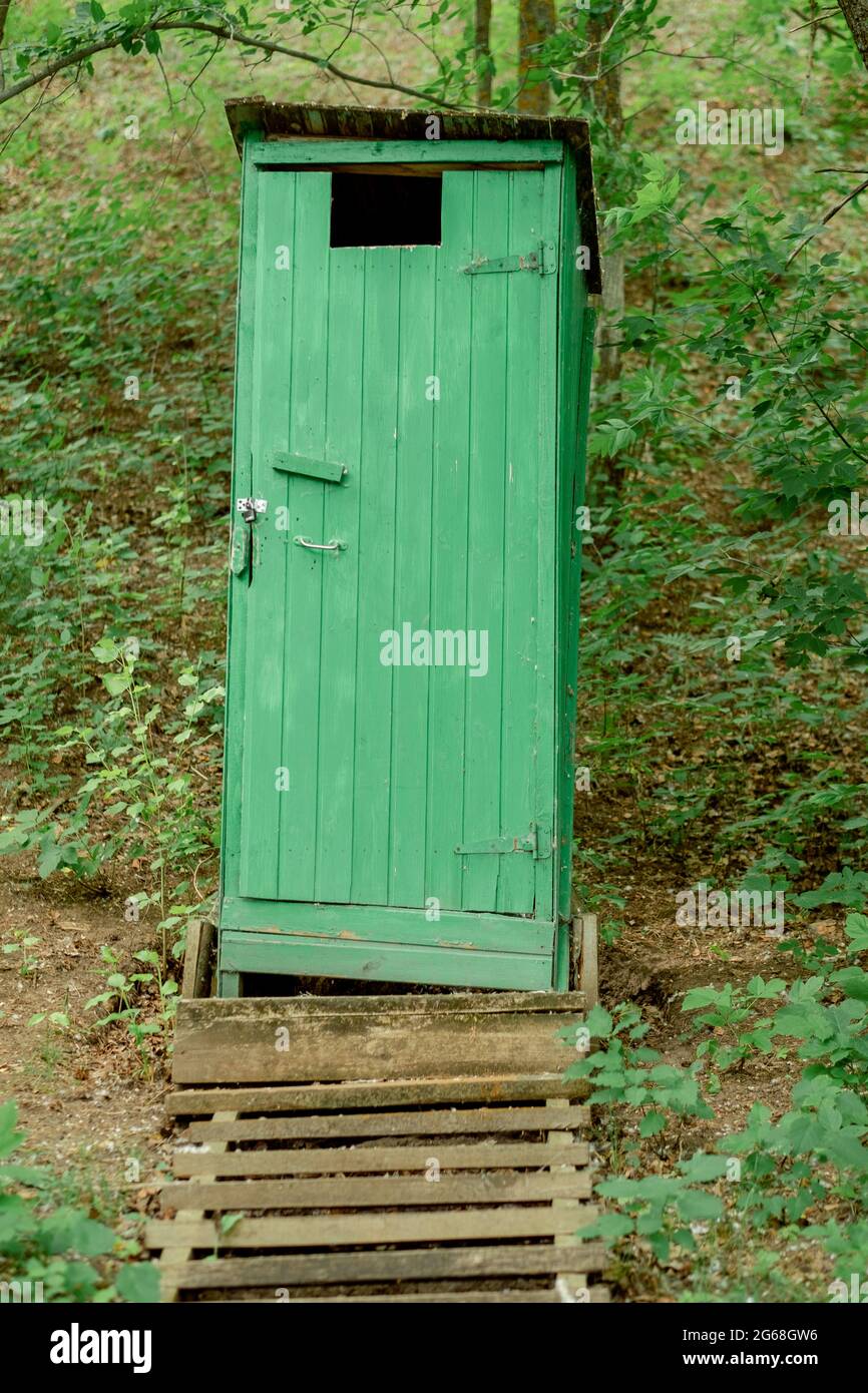 Ancienne toilette en bois vert dans un style rustique avec des escaliers et  une fondation solide dans la forêt. toilettes en bois enfermées dans le  parc. Structure verticale simple Photo Stock -