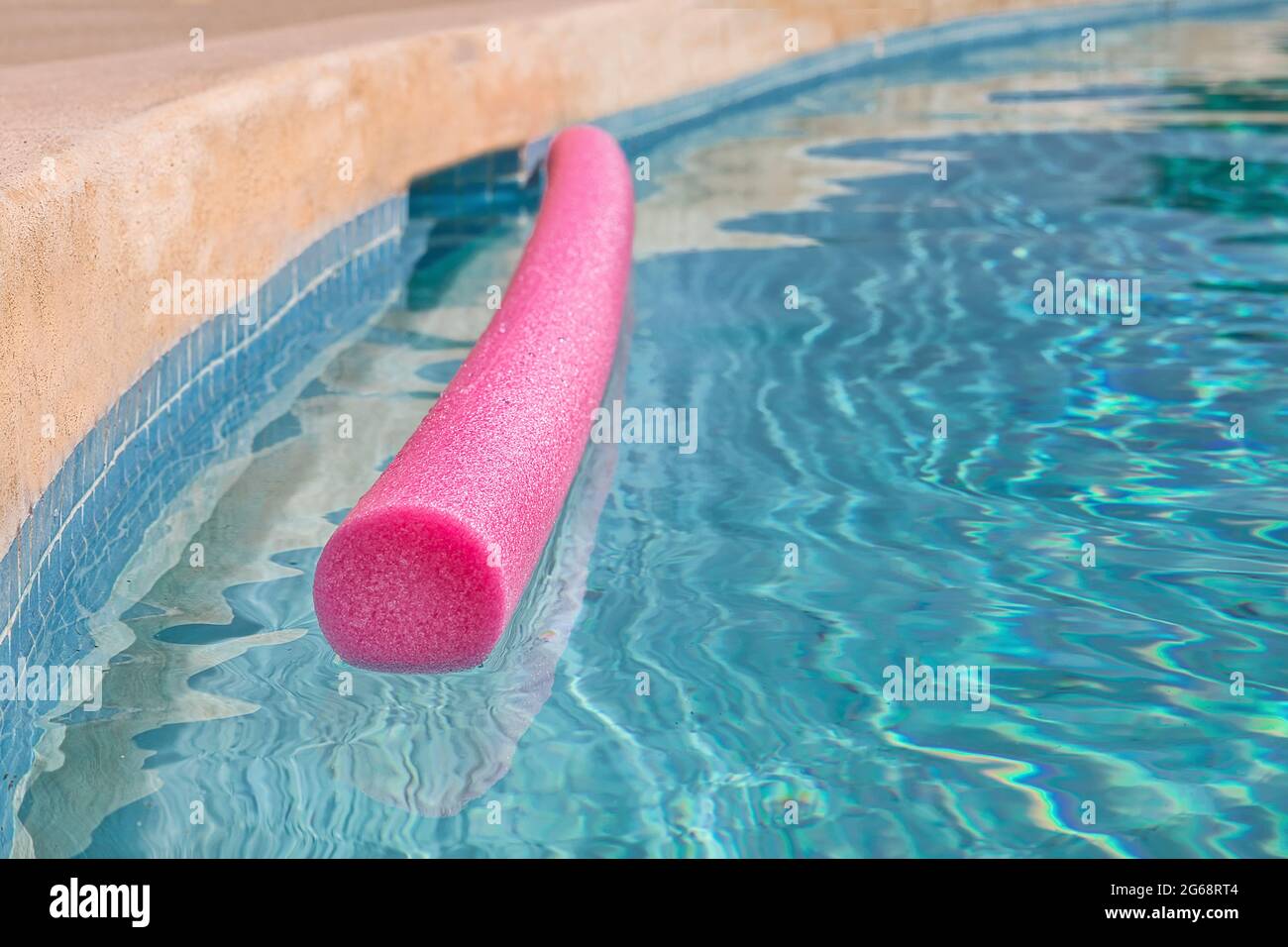 Piscine avec flotteur. Gros plan. Mise au point à l'avant. Isolé. Serpent flottant rose avec des ondulations abstraites d'eau. Image de stock. Banque D'Images