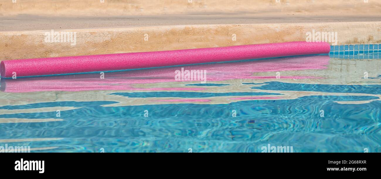 Piscine avec flotteur. Gros plan. Copier l'espace. Serpent flottant rose avec des ondulations d'eau rose abstraites. Image de stock. Banque D'Images