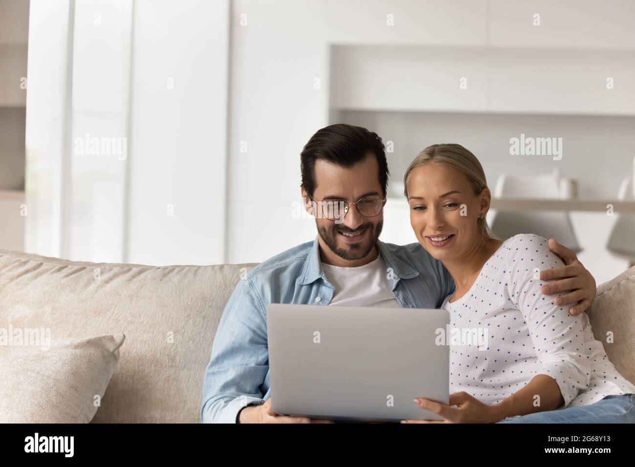 Un jeune couple heureux utilisant un ordinateur portable pour se détendre sur un canapé ensemble Banque D'Images