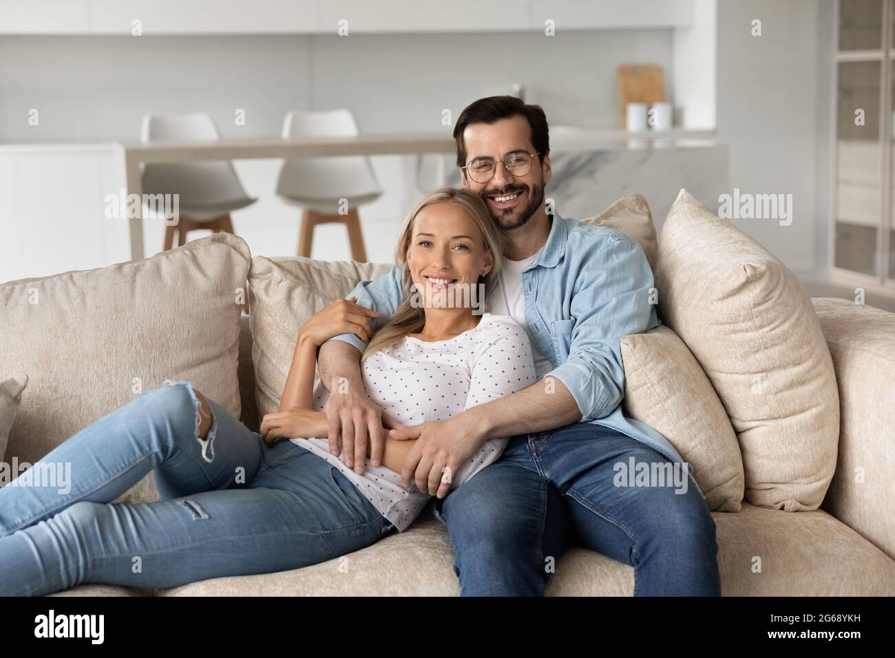 Portrait d'un jeune couple souriant qui s'embrasse assis sur un canapé confortable Banque D'Images