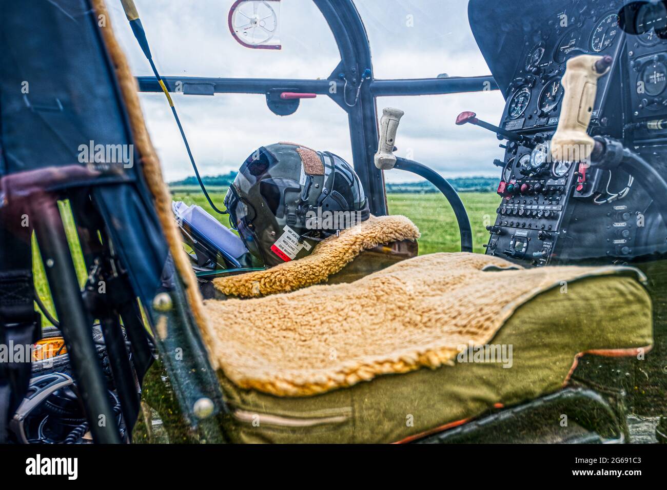 Casque pilote à l'intérieur du poste de pilotage d'un hélicoptère 1961 Sud-Aviation se 3130 Alouette avec sièges recouverts de peau de mouton, ailes et roues, Middle Wallop, Royaume-Uni Banque D'Images