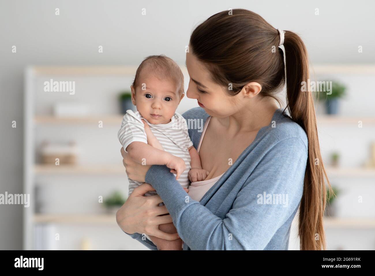 Portrait d'une jeune mère heureuse tenant un petit bébé mignon entre les mains Banque D'Images