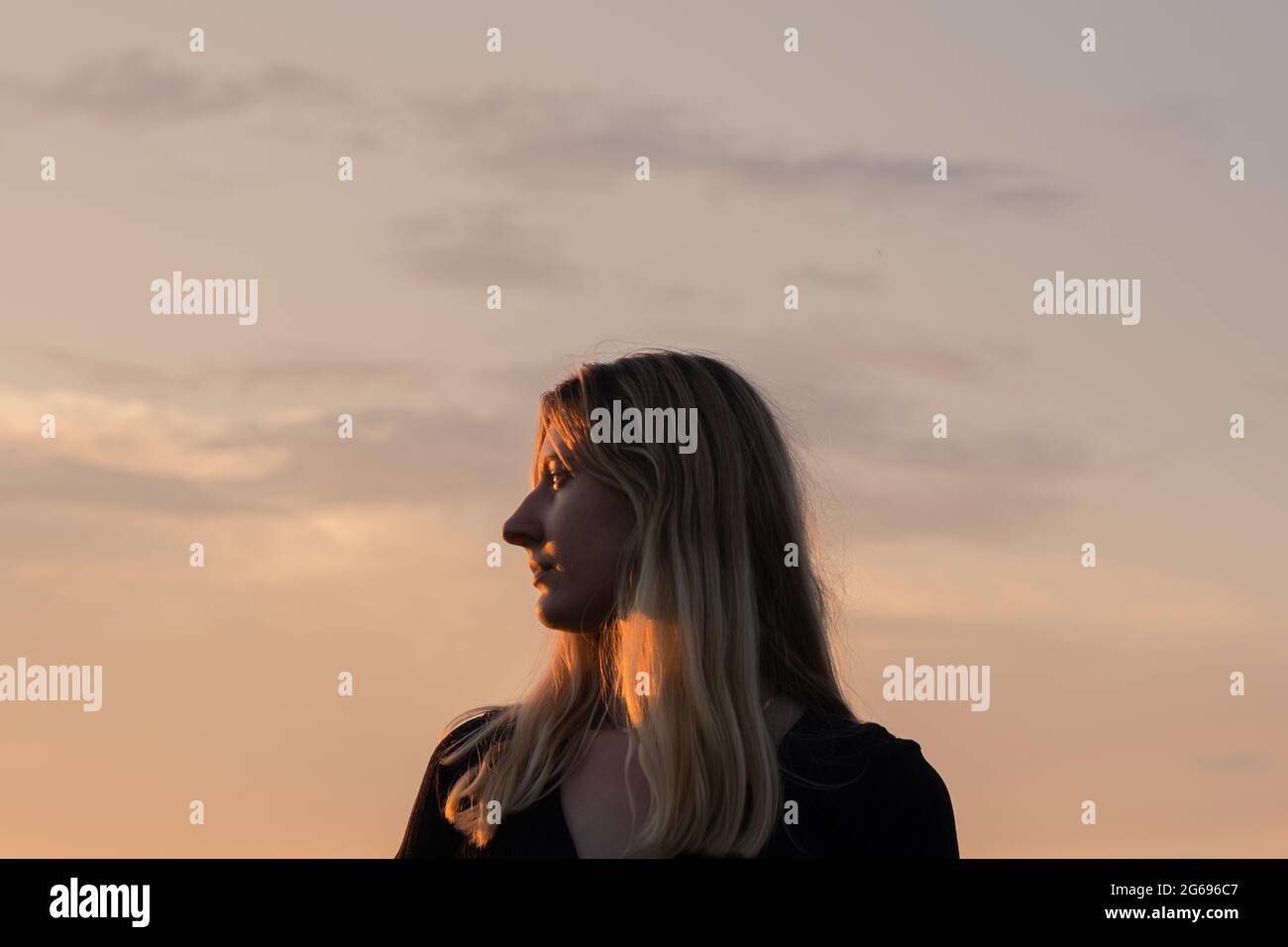 Portrait d'une femme au soleil du soir. Portrait de profil d'une femelle caucasienne rétroéclairé par le coucher de soleil contre le ciel Banque D'Images