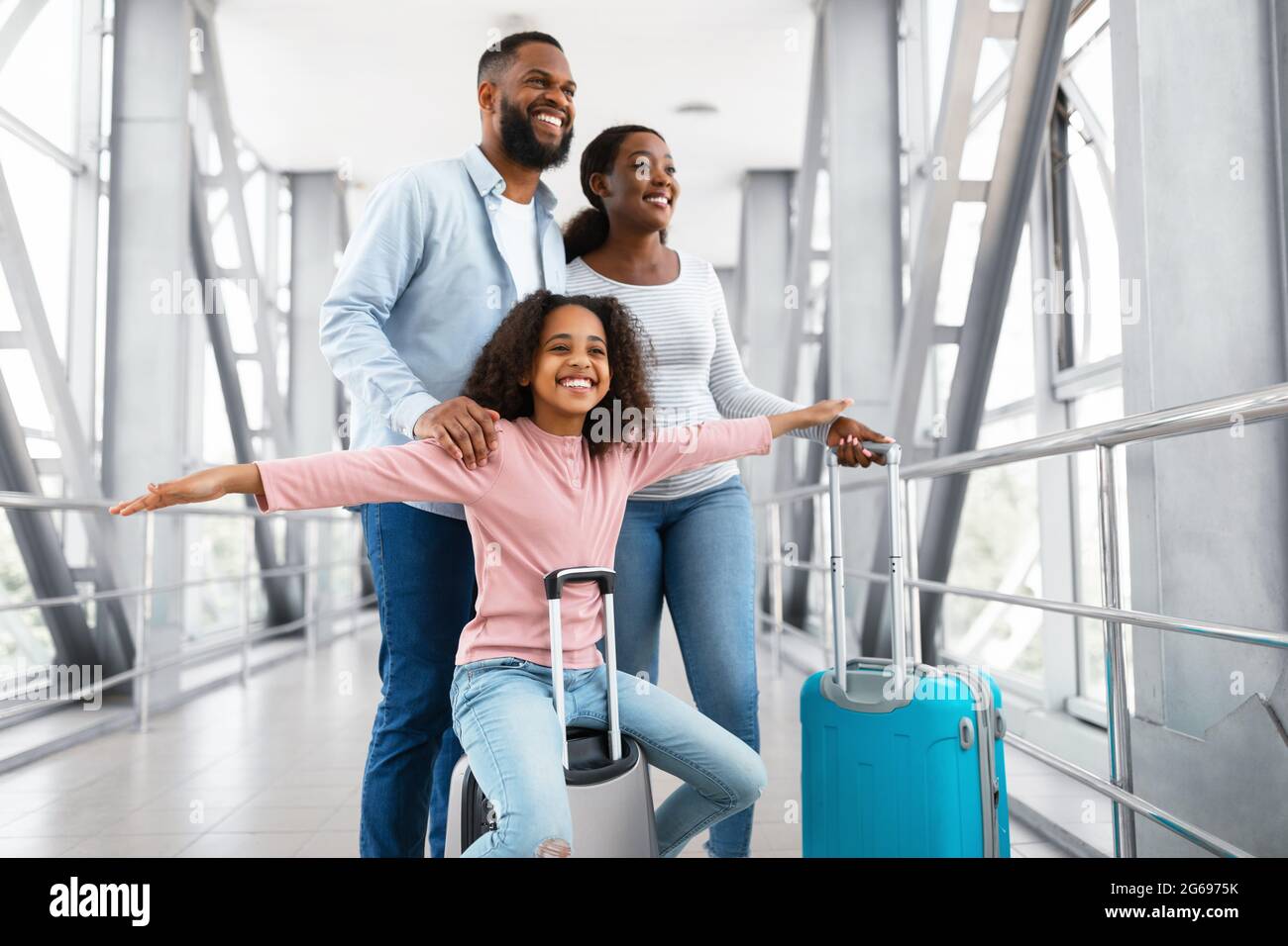 Bonne famille noire voyageant avec un enfant, marchant à l'aéroport Banque D'Images