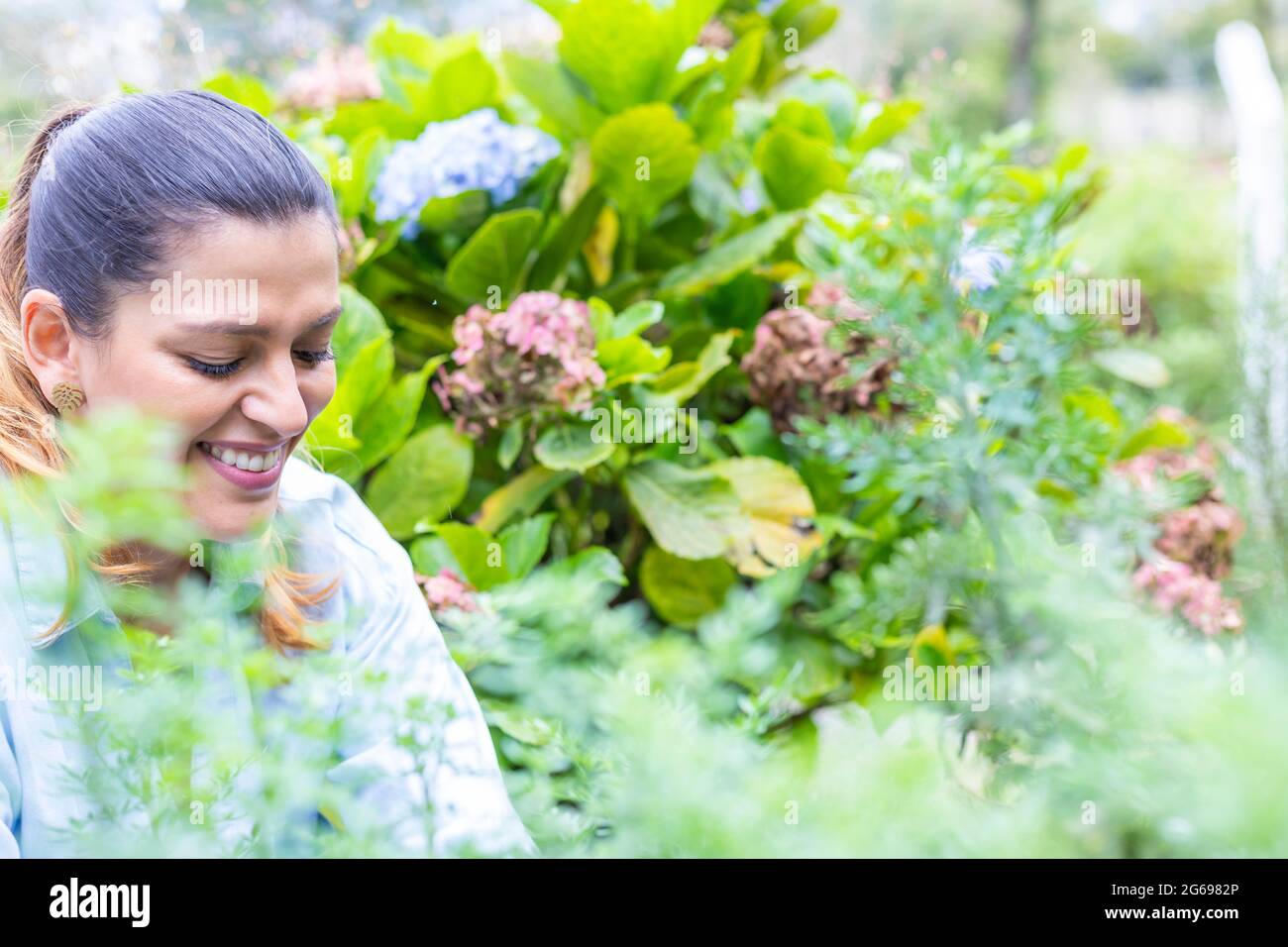 foyer sélectif d'une femme souriante au milieu de ses plantes de jardin Banque D'Images