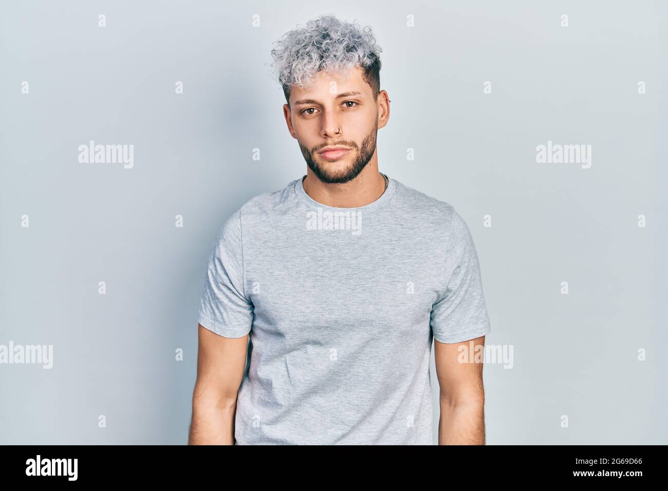Jeune homme hispanique aux cheveux teints modernes portant un t-shirt gris  décontracté avec une expression sérieuse sur le visage. Simple et naturel  regarder l'appareil photo Photo Stock - Alamy