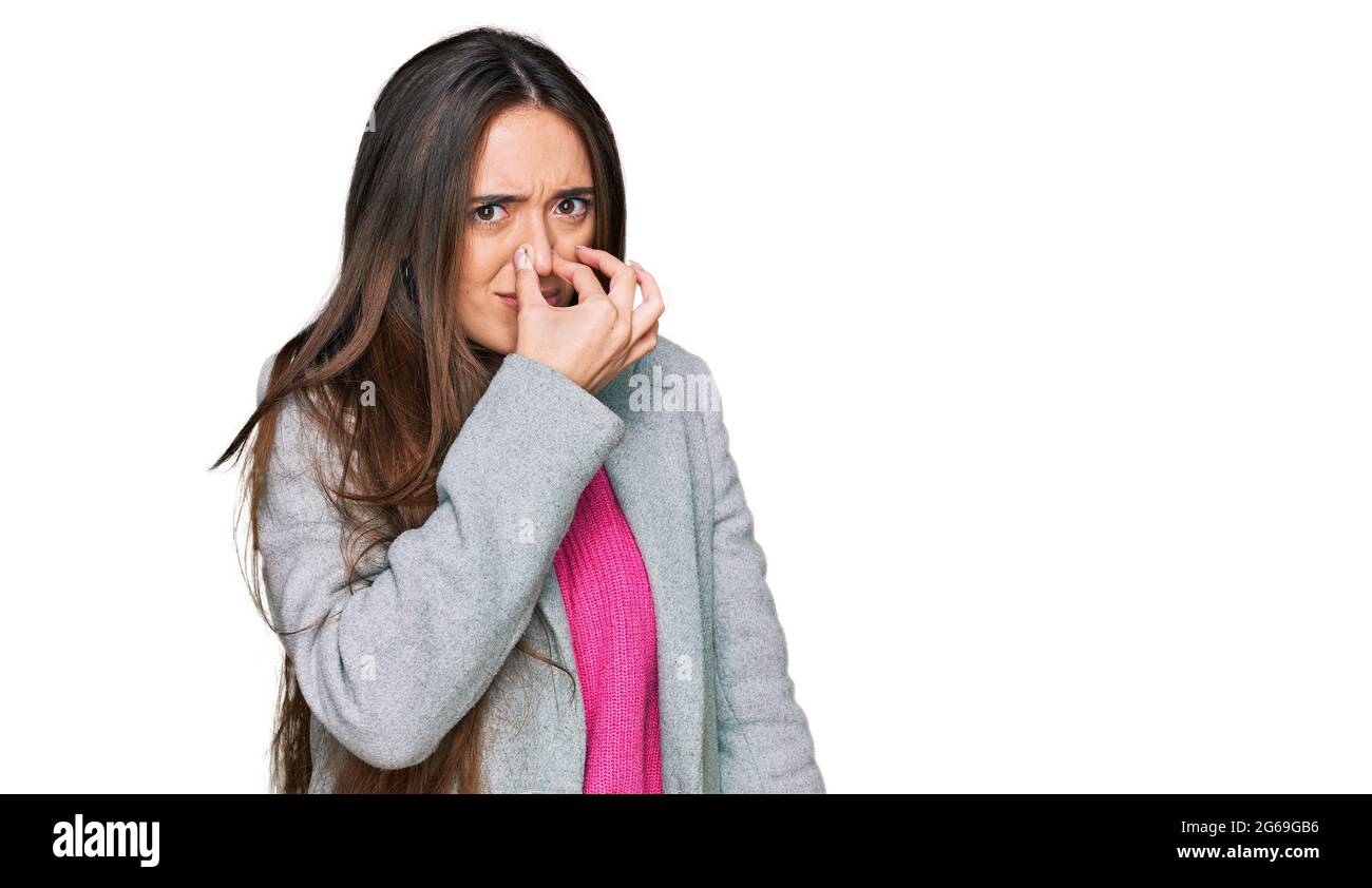 Une jeune fille hispanique portant des vêtements d'affaires sent quelque chose d'original et de dégoûtant, une odeur intolérable, tenant l'haleine avec les doigts sur le nez. Mauvaise pme Banque D'Images