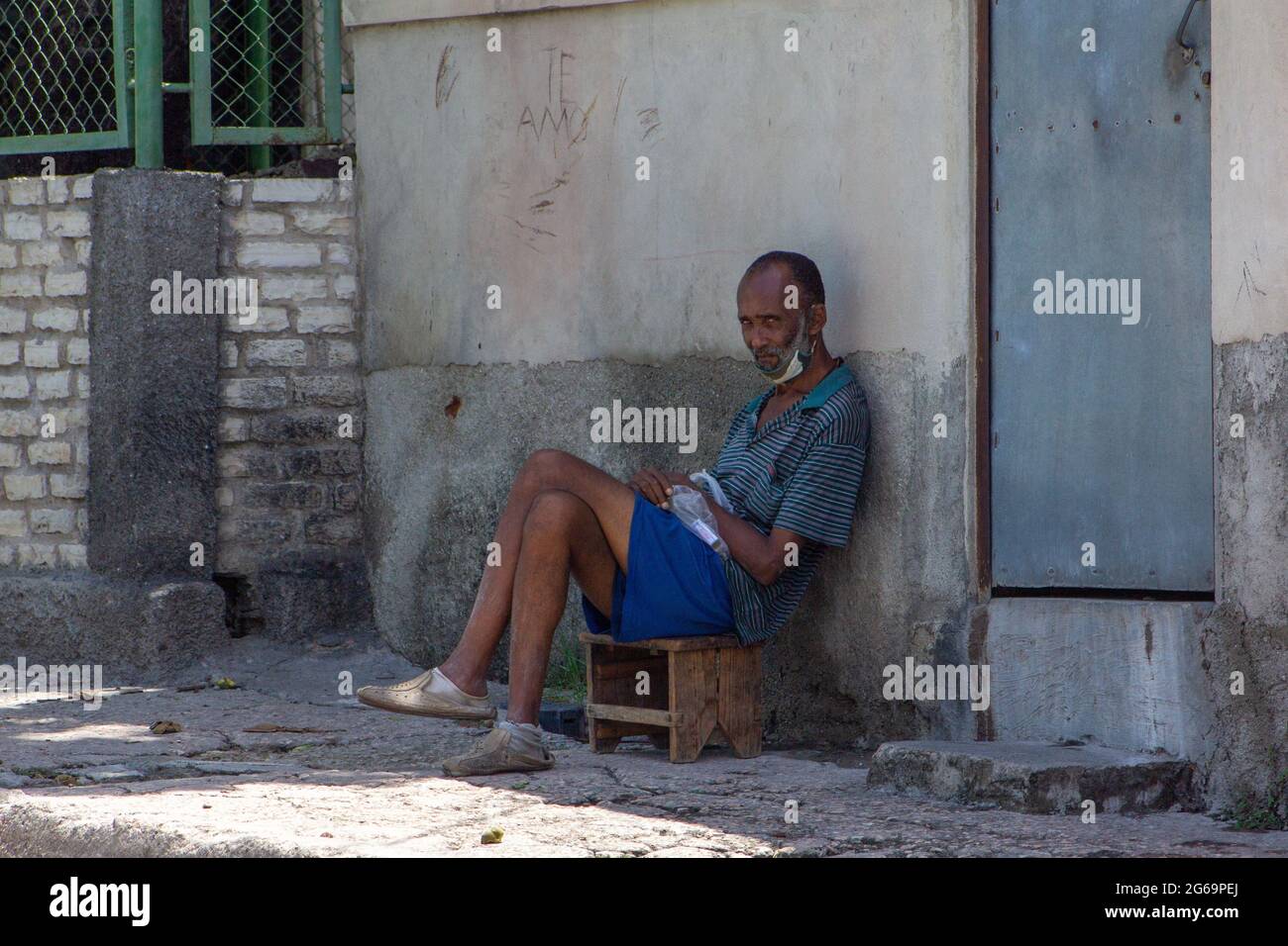 Homme cubain assis dans un siège en bois devant sa maison à Santiago de Cuba, Cuba Banque D'Images