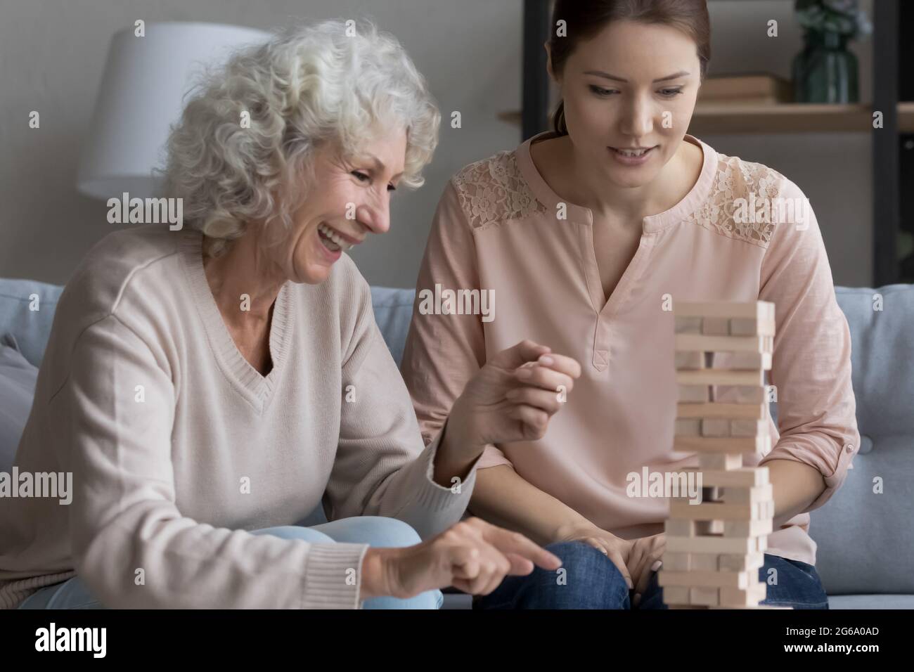 Une mère mûre riante joue dans une tour tumbling avec une fille adulte Banque D'Images