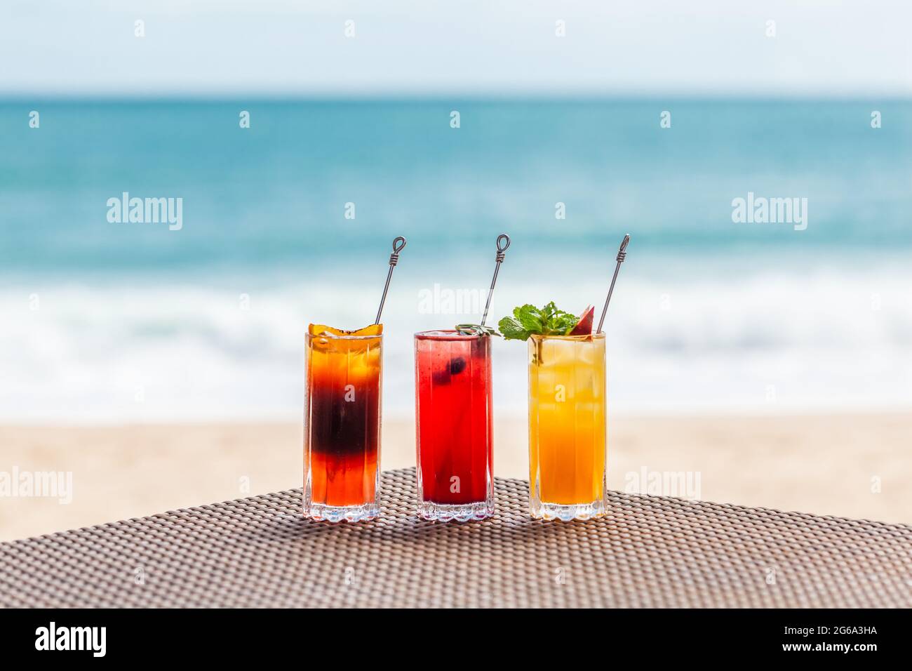 Cocktails aux baies lumineuses et saines à la table sur la plage avec la mer bleue sur le fond Banque D'Images