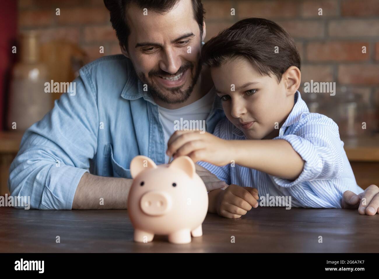 Un papa heureux enseignant à un petit fils intelligent pour économiser de l'argent Banque D'Images