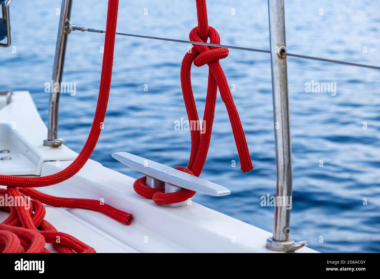 Bateau à voile amarrer des cordes sur le pont. Corde de yachting de couleur rouge attachée sur la cale, l'espace, le modèle de carte de croisière. Voilier sécurisé, outils et équipement clos Banque D'Images