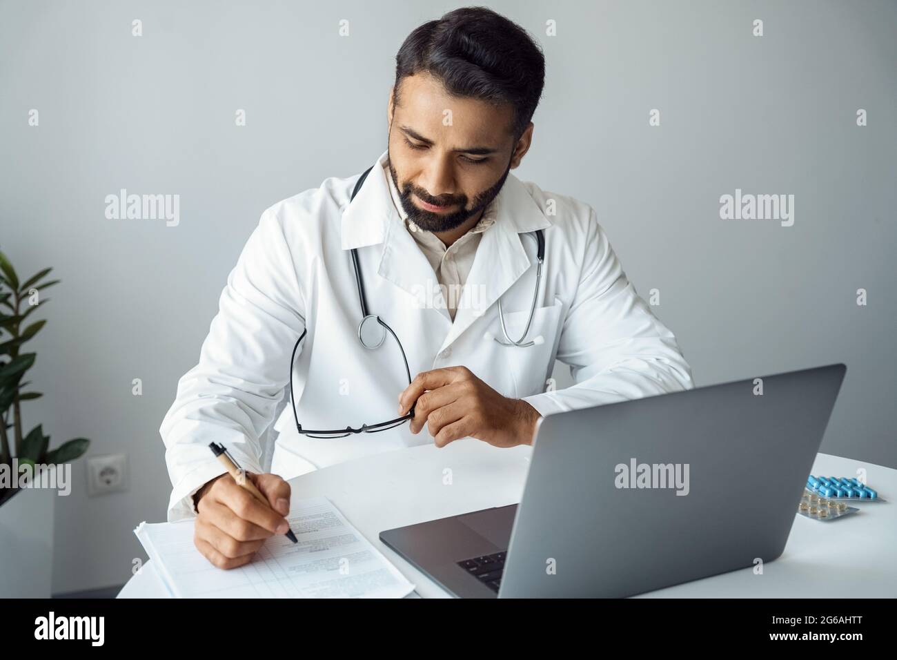 Le médecin écrit le diagnostic du patient sur la consultation en ligne, assis devant l'ordinateur portable Banque D'Images
