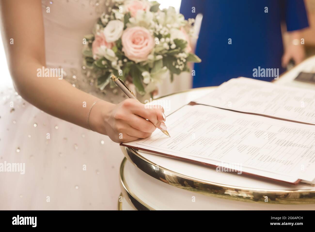 La main d'une jeune mariée met une signature sur consentement au mariage dans le document au bureau d'enregistrement. Banque D'Images