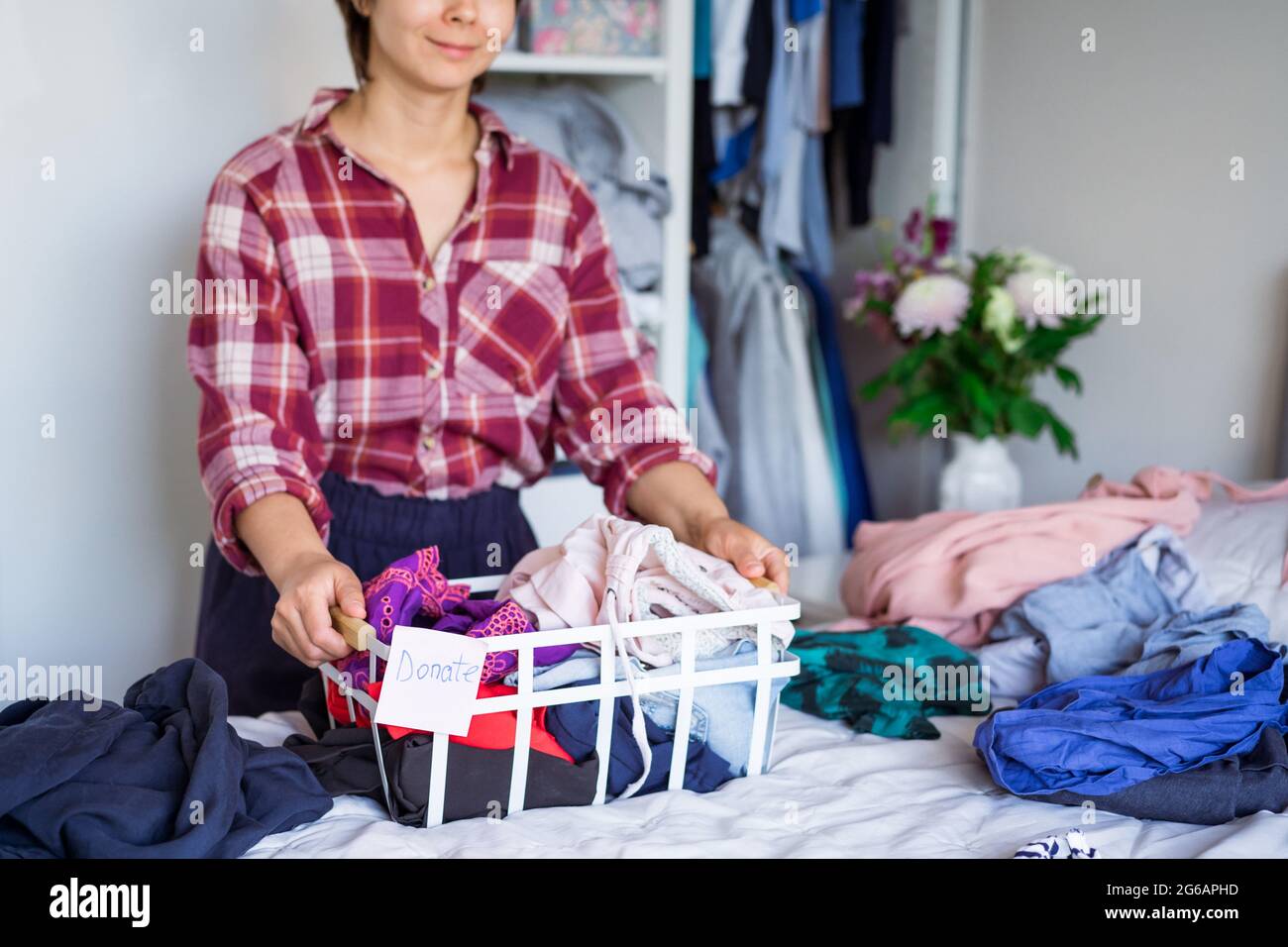 Une femme avec une sélection de vêtements de sa garde-robe pour faire un don dans une boutique de la Charité. Femme Decluttering vêtements, Tri, et nettoyage. Réutilisation, deuxième ha Banque D'Images