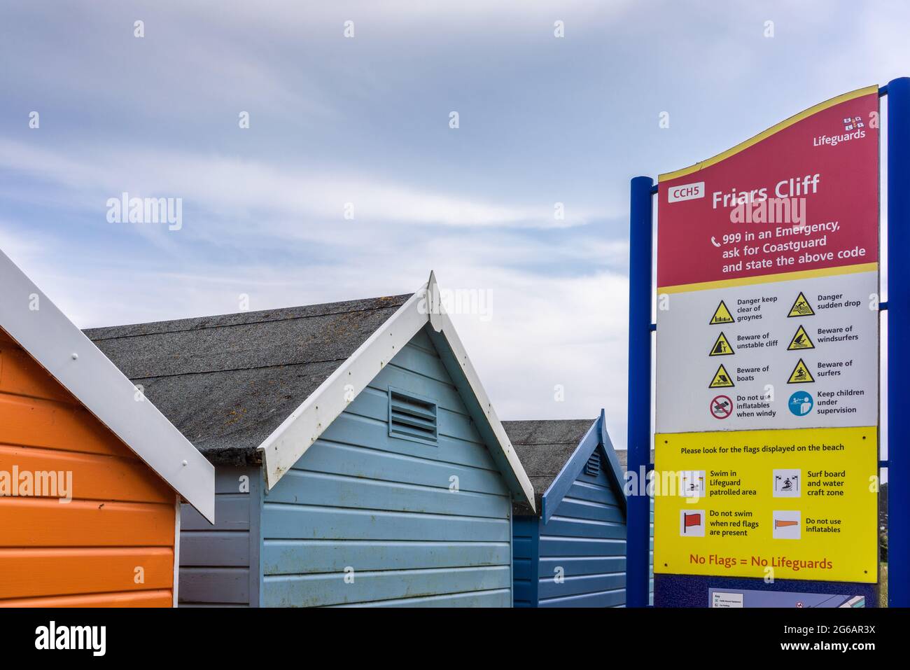 Huttes de plage colorées et signalisation à Friars Cliff Beach à Dorset, Angleterre, Royaume-Uni Banque D'Images