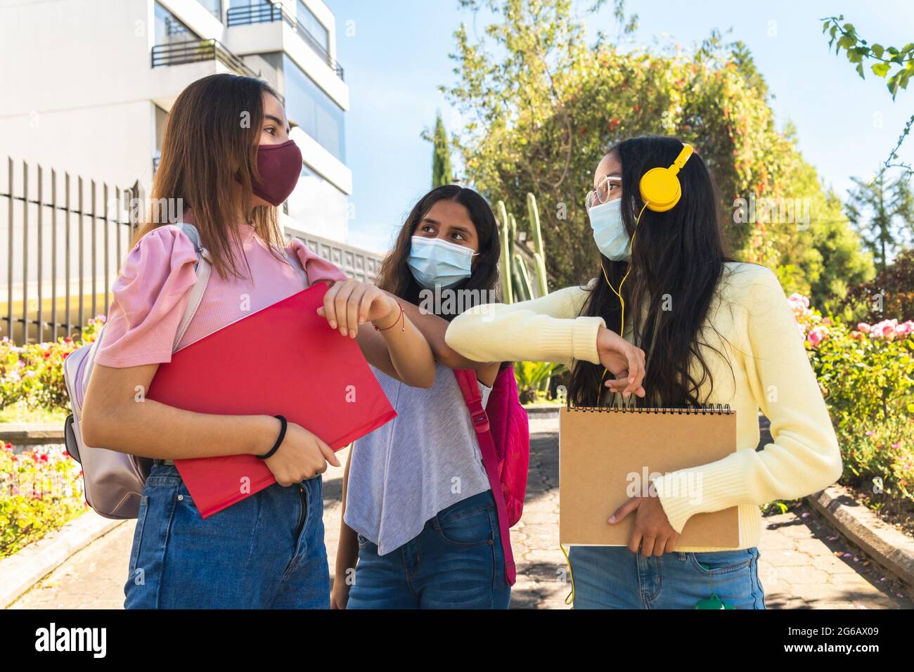 Gros plan de trois amis latina adolescents avec des masques, saluez avec les coudes au retour à l'école pour la prévention du coronavirus pendant le p Banque D'Images