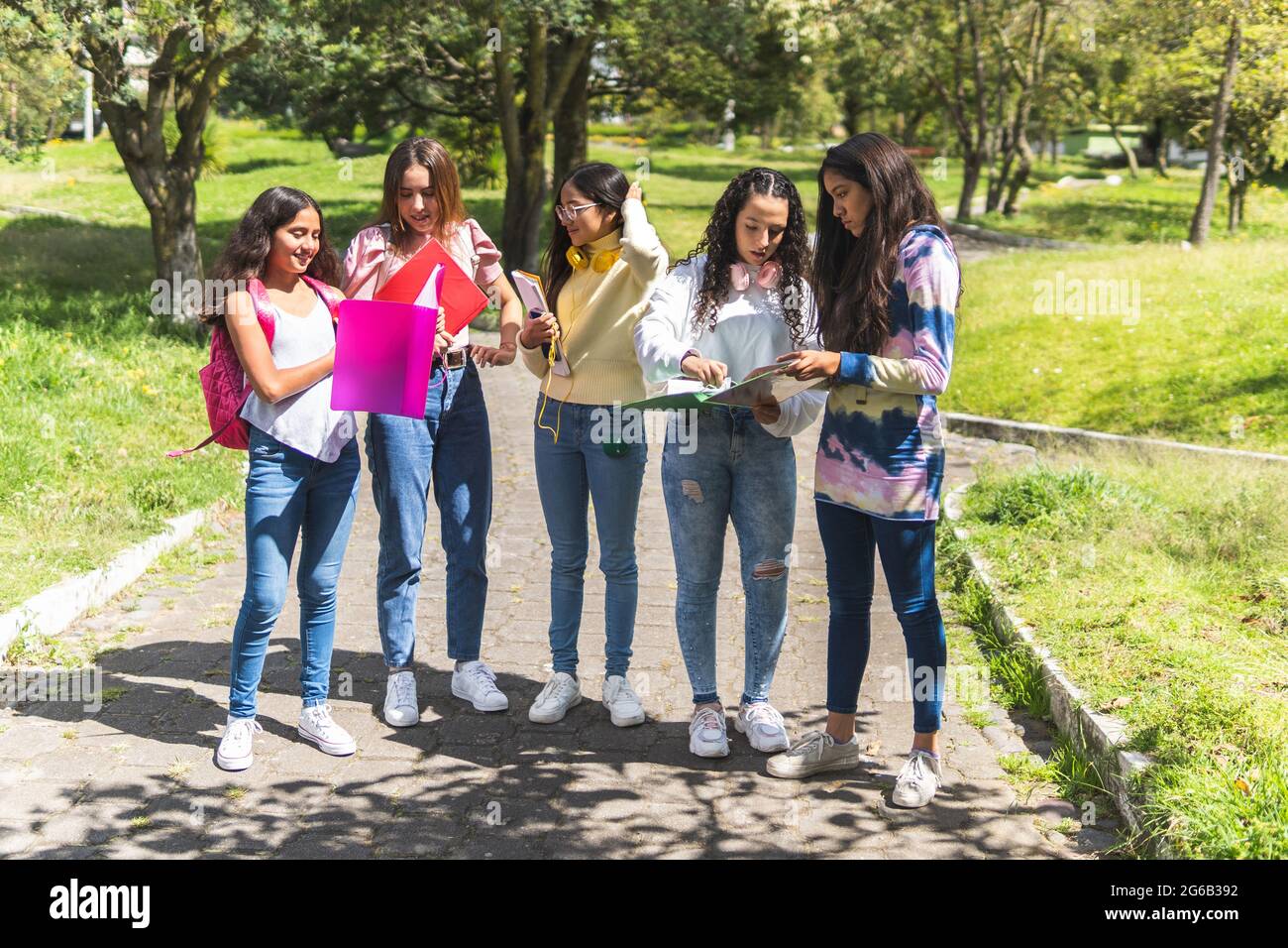 Groupe d'étudiants latino-américains adolescents avec leurs sacs à dos et leurs carnets examinant leurs devoirs à l'extérieur. Concept de retour à l'école Banque D'Images