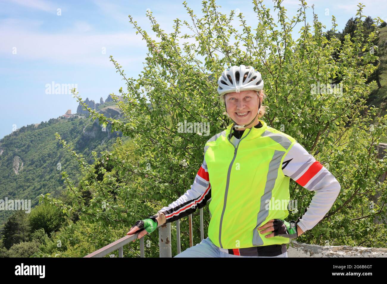 Portrait d'une femme cycliste souriante sur fond de roche d'ai-Petri, Yalta, Crimée, Russie. Cycliste portant un casque et un voyage réfléchissant v Banque D'Images