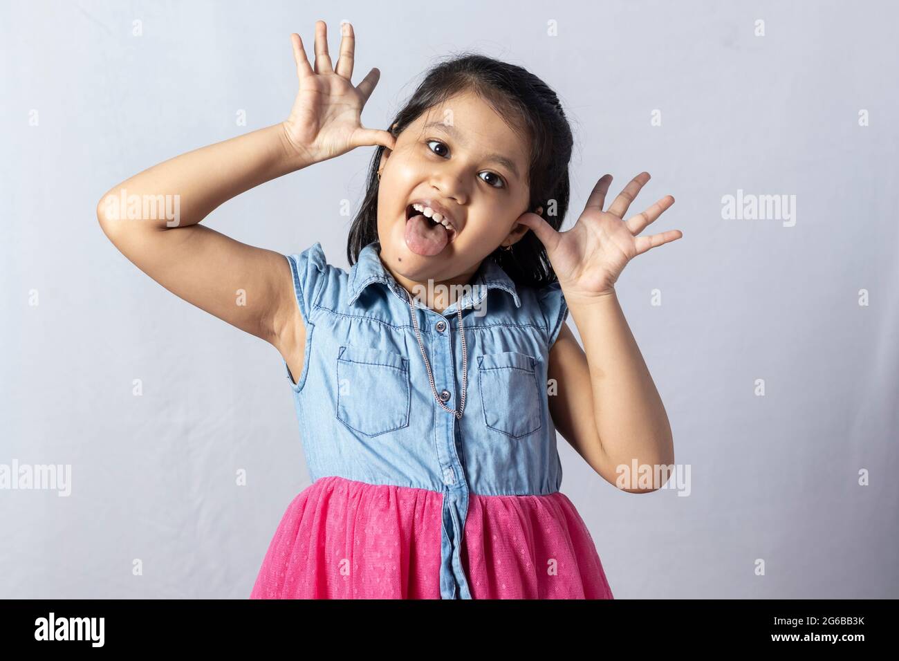 Une jolie petite fille indienne mignonne faisant un visage isolé sur fond blanc Banque D'Images