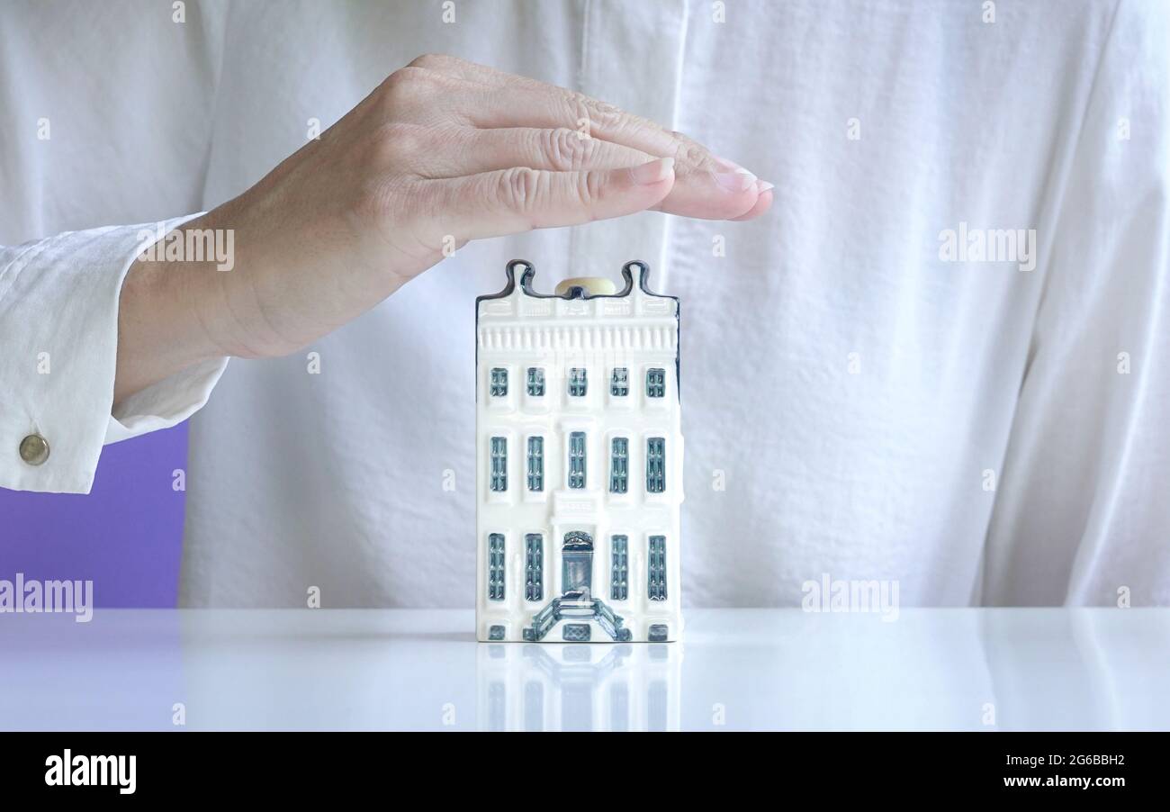 Maison appartement miniature couverte à la main. Concept d'assurance de biens. Banque D'Images