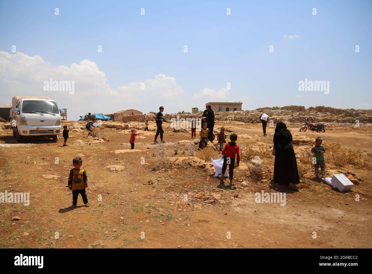4 juillet 2021 : Alep, Syrie, 04 juillet 2021. L'aide est fournie aux civils déplacés dans un camp de Datrat Izza, au nord-ouest d'Alep. Actuellement, l'aide humanitaire atteint la zone tenue par les rebelles dans le nord-ouest de la Syrie par le poste frontalier de Bab Al-Hawa, que le Conseil de sécurité de l'ONU a approuvé en 2014, trois ans après le début du conflit syrien. L'ONU doit tenir un vote le 10 juillet pour discuter du renouvellement de l'autorisation d'aide au transit par le passage à niveau. Les organisations humanitaires locales et internationales ont souligné que le passage est la seule ligne de vie pour le nord-ouest de la Syrie et Banque D'Images