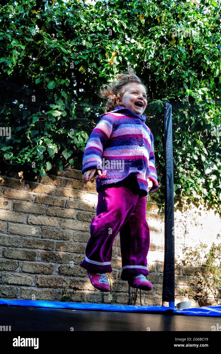 Bonne fille sautant sur un trampoline dans le jardin, Italie Banque D'Images