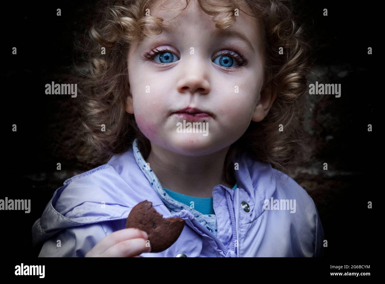 Portrait d'une fille souriante mangeant un cookie Banque D'Images