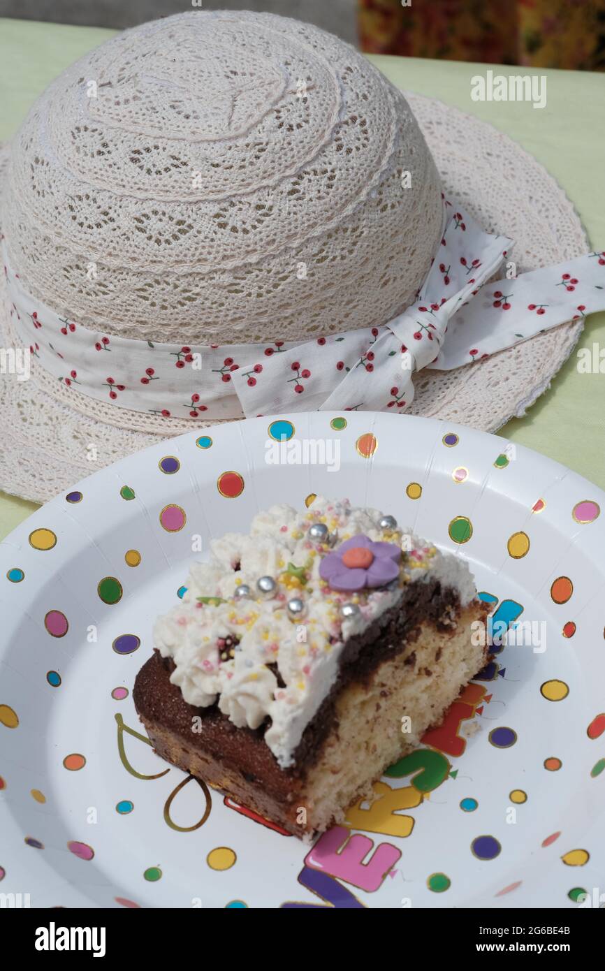 Tranche de gâteau d'anniversaire avec glaçage sur une assiette à côté d'un chapeau d'été Banque D'Images