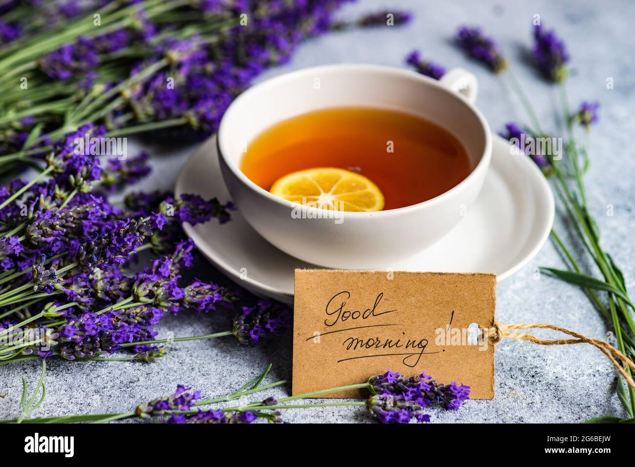 Tasse de thé avec une tranche de citron, fleurs de lavande et une étiquette du matin sur une table Banque D'Images