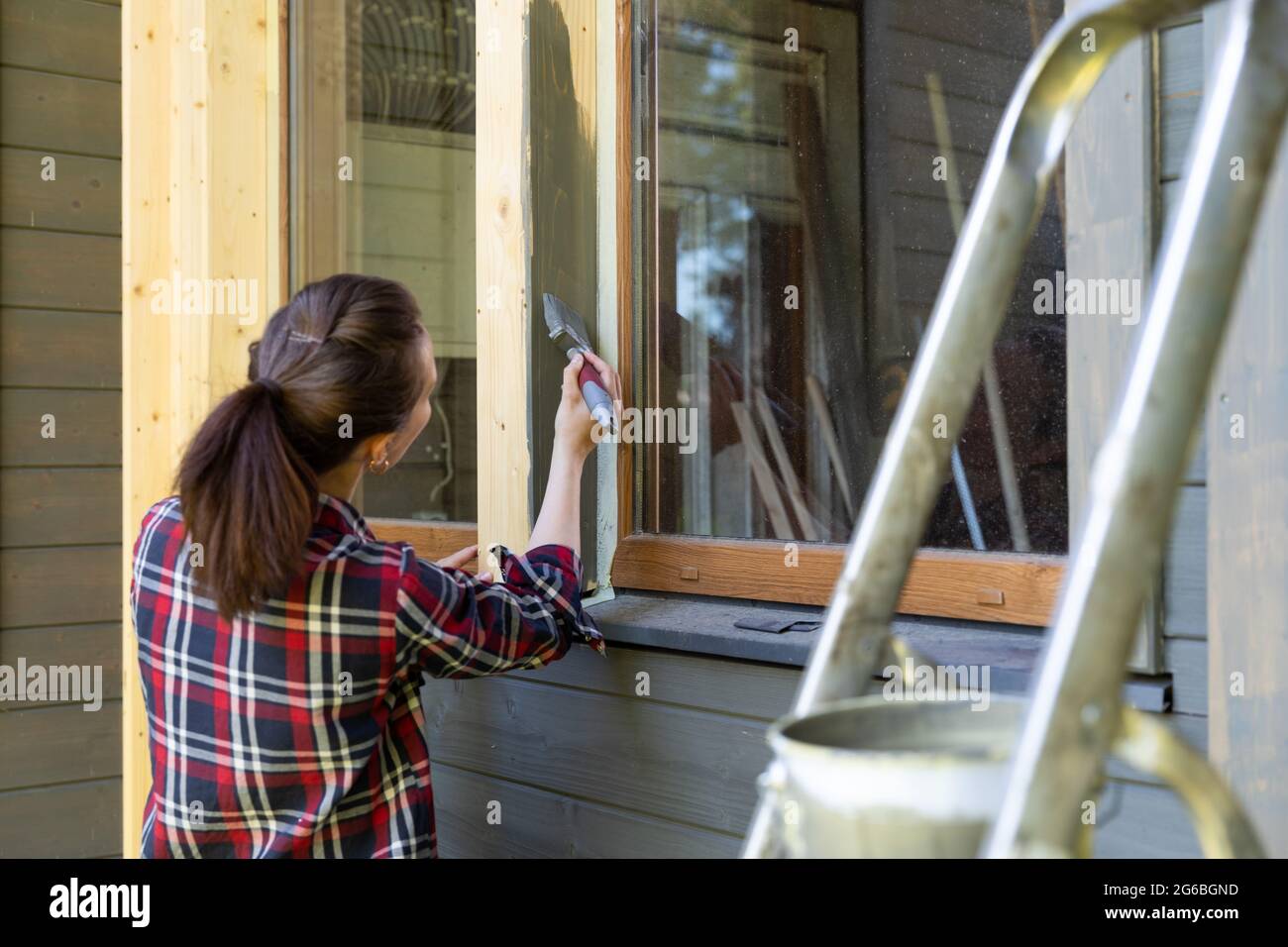 Femme ouvrier peinture maison en bois mur extérieur avec pinceau et bois  couleur de protection maison concept d'amélioration Photo Stock - Alamy