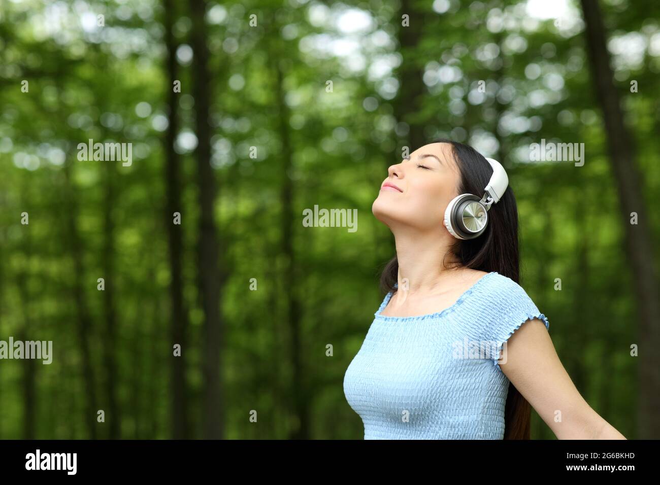 Femme asiatique qui écoute de la musique avec des écouteurs respirent de l'air frais dans une forêt Banque D'Images