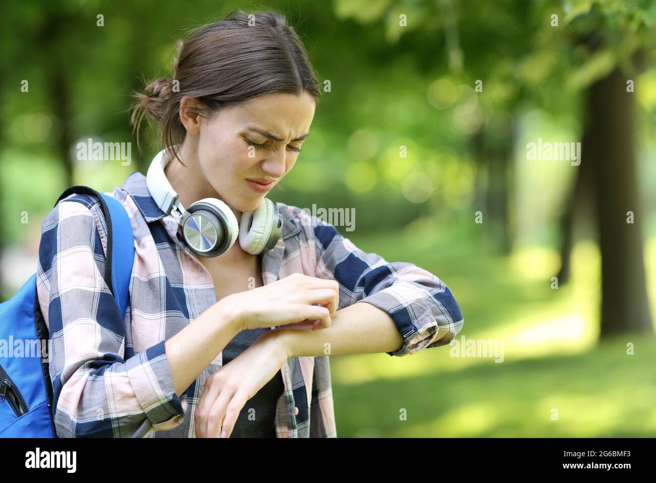 Un étudiant allergique se grattant le bras dans un parc ou un campus Banque D'Images