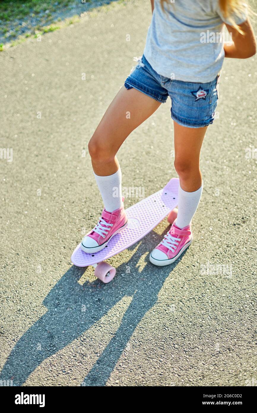 Petite fille apprenant à utiliser un skateboard, enfant anonyme portant des  chaussettes blanches et des chaussures roses à cheval skateboard sur une  rue rurale de la ville d'été Photo Stock - Alamy