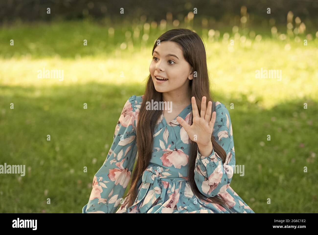 Petite fille long cheveux robe tendance se détendre dans le parc ensoleillé  jour nature fond, dire bonjour concept Photo Stock - Alamy
