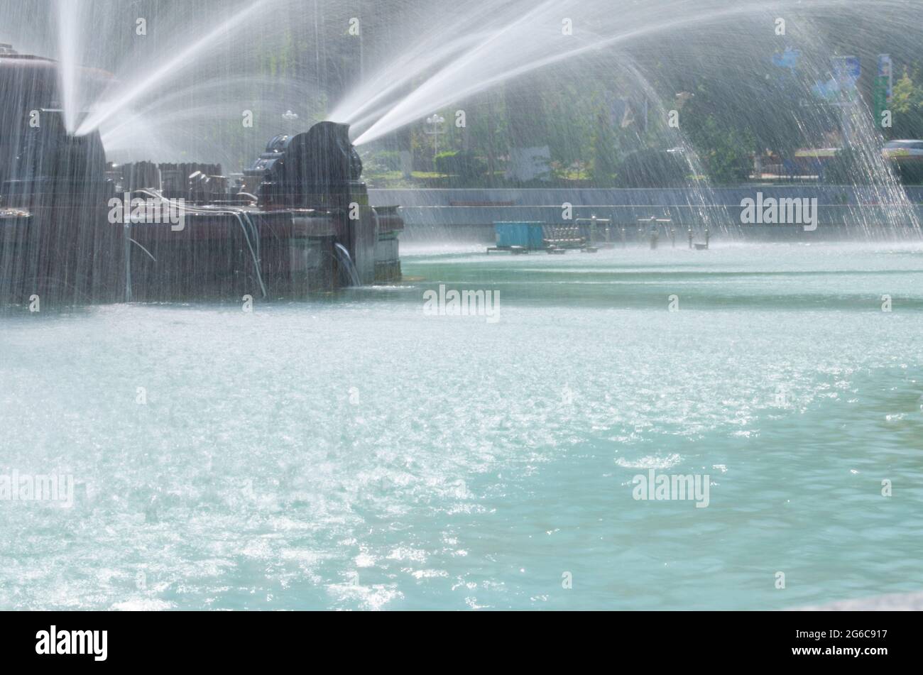 Jets et gouttes d'eau de la fontaine dans la piscine d'eau bleue du parc Banque D'Images