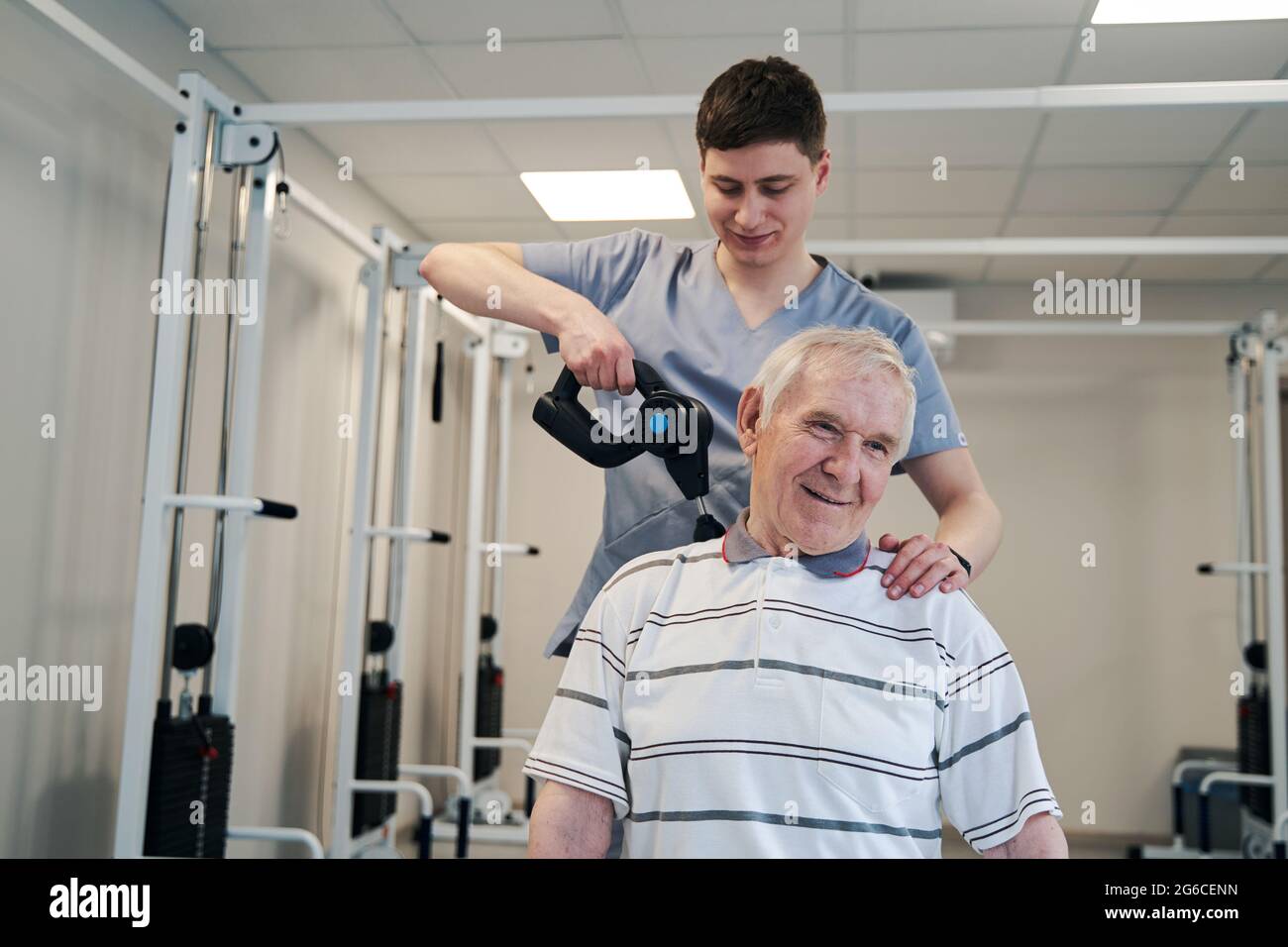 Thérapeute physique avec pistolet de massage musculaire traitant le patient Banque D'Images