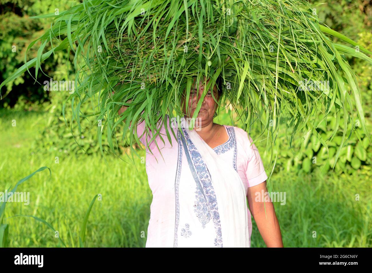 Femme Farmer portant l'herbe verte sur sa tête Banque D'Images