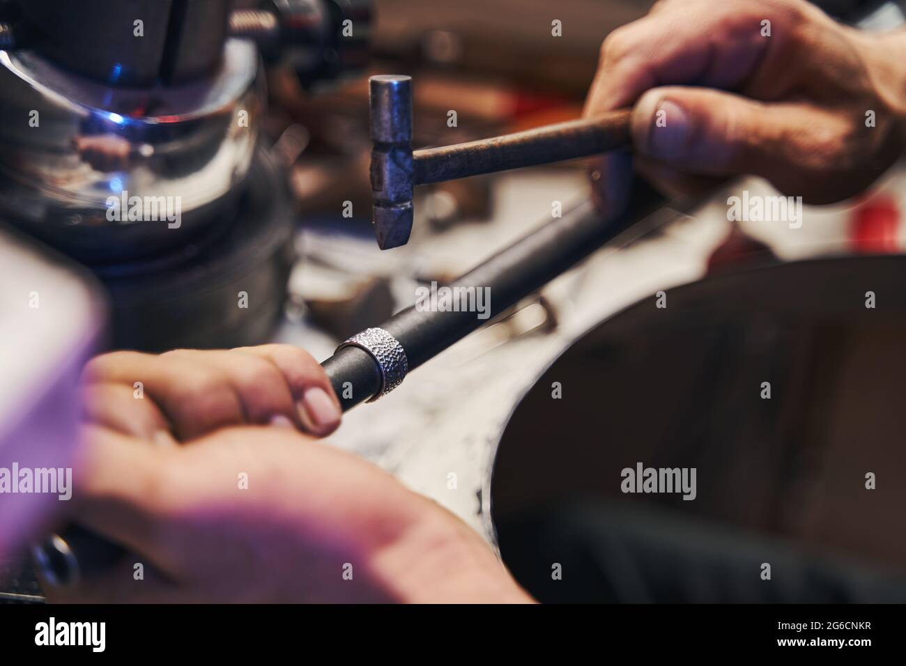 Un ouvrier d'atelier de Goldsmith frappe l'anneau avec un marteau à panne ronde Banque D'Images