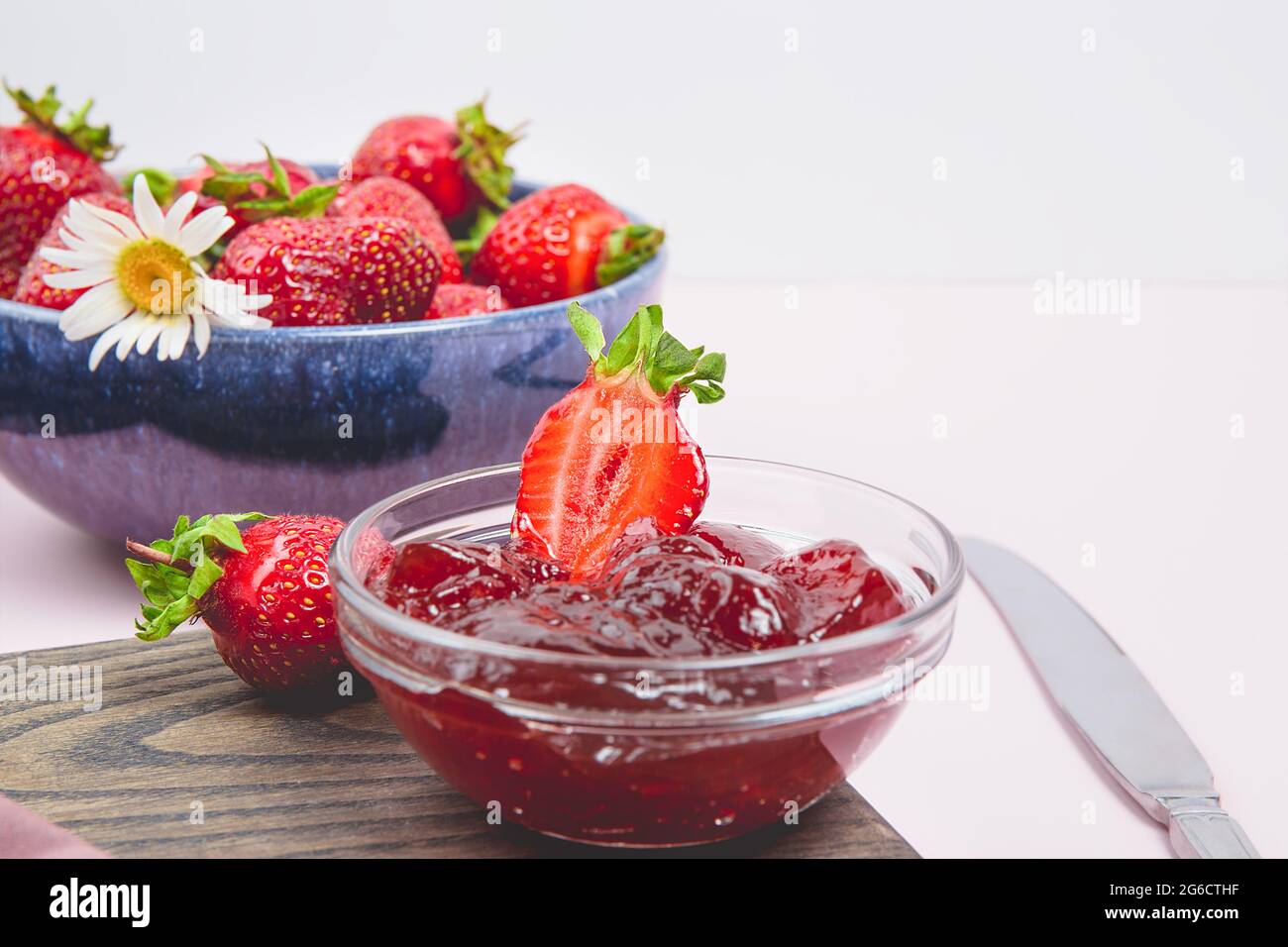 Confiture de fraises maison ou gelée de fraises avec des fraises fraîches mûres sur une assiette blanche. Petit déjeuner avec pain grillé et confiture de fraises. Couteau pour s Banque D'Images